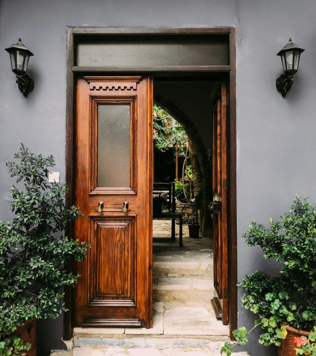 Explore a rustic wooden doorway leading to a lush courtyard in Yukarı Lefkara, Cyprus.